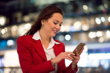 Bir şehirde gece cep telefonunu kullanan kadın