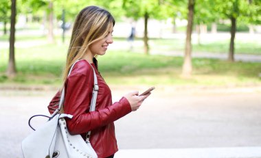 Akıllı telefonunu kullanırken parkta yürüyen kadın