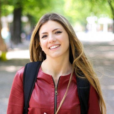 Parkta açık havada yürüyen ve gülümseyen kız öğrenci