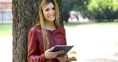 Genç kadın bir ağaç parkta karşı yalan ve kablosuz internet bağlantısı özgürlüğü zevk dijital tablet kullanma