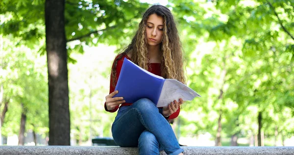 美丽的女大学生在公园的长椅上看书 — 图库照片