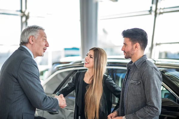 Happy Young Family Shaking Hands Salesman Choosing New Car Showroom — Stock Photo, Image