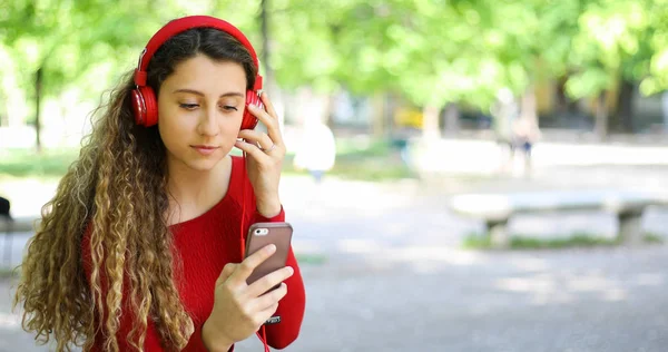 Woman listening to music sitting on bench in a park