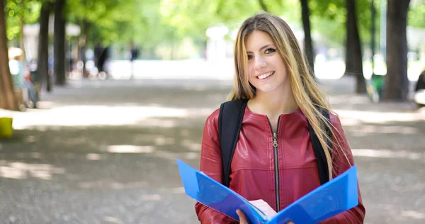 公園で本を持ち 笑顔を浮かべていた女子学生 — ストック写真