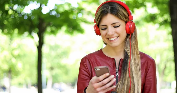 Woman listening to music sitting on bench in a park