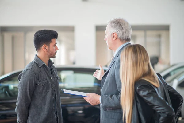 Feliz Jovem Família Conversando Com Vendedor Escolhendo Seu Novo Carro — Fotografia de Stock