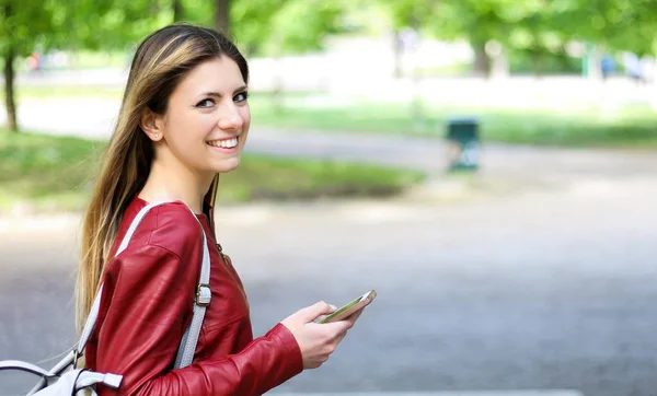 Akıllı Telefonunu Kullanırken Parkta Yürüyen Kadın — Stok fotoğraf