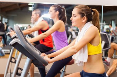 Spor salonunda bisiklet süren mutlu insanlar.