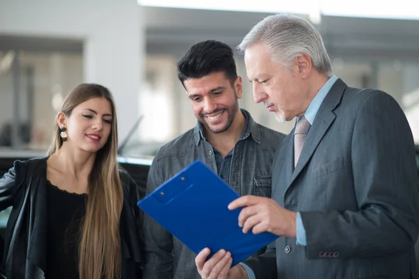 Feliz Familia Joven Hablando Con Vendedor Una Sala Exposición Coches — Foto de Stock