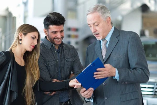 Feliz Jovem Família Conversando Com Vendedor Showroom Carro — Fotografia de Stock