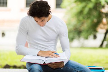 Yakışıklı genç adam parkta bankta kitap okuma