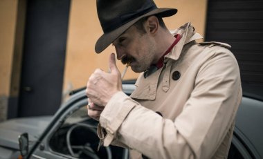 Onun Vintage arabanın önünde beklerken bir sigara aydınlatma Mobster