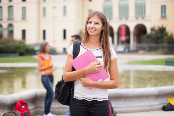 Portrait of a smiling female student in front of her college