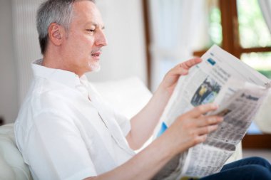 Olgun adam oturma odasında bir gazete okuma