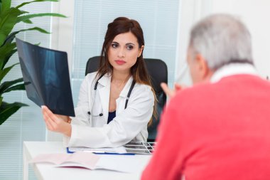 Doktor hastasıyla birlikte radyografiyi inceliyor.