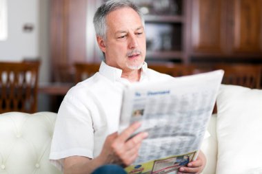 Olgun adam oturma odasında bir gazete okuma