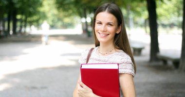 Parkta kitap tutan gülümseyen öğrenci 