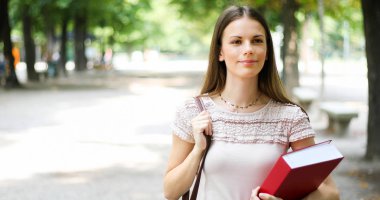 Parkta kitap tutan kız öğrenci