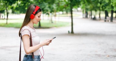 Akıllı telefonunu kullanırken parkta yürüyen kadın