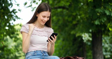 Çok mutlu kadın onun akıllı telefon üzerinden iyi haber okuma