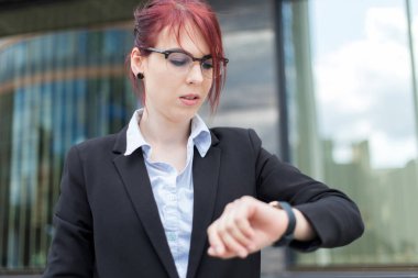 Kendine güveni tam bir bayan yönetici. Saati kontrol ediyor.