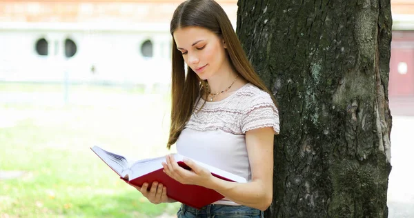 微笑的学生在树边看书 — 图库照片
