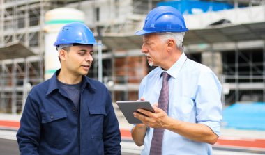 İnşaat alanındaki bina planlarını inceleyen iki mimar.