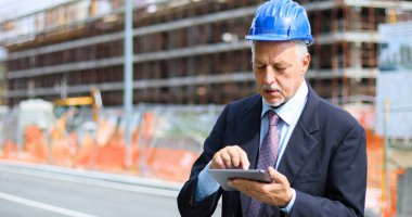 Kıdemli mühendis erkek takım elbise ve tablet PC'de çalışma kask
