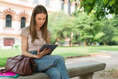 Okulun önündeki parkta ders çalışan bir kız öğrencinin portresi.