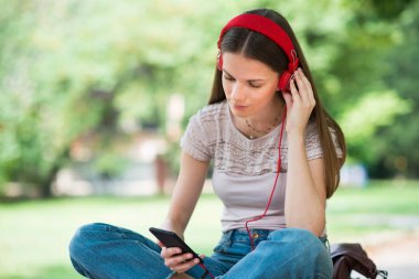 Genç kız telefonundan müzik dinliyor.