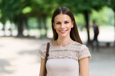 Parkta gülümseyen güzel bir kadın.