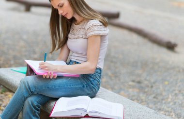 Okulun önündeki parkta ders çalışan bir kız öğrencinin portresi.