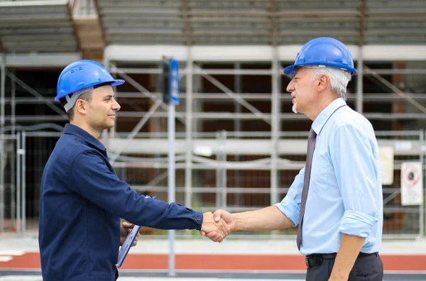 Két Mérnök Kézfogást Egy Építkezésen — Stock Fotó