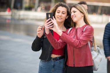 Kadın arkadaşlar birlikte cep telefonu kullanarak