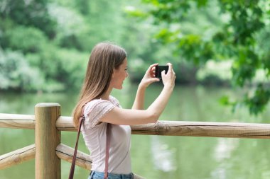 Young woman using her mobile phone to take a photo clipart