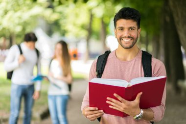 Mutlu erkek öğrenci arkasinda arkadaslariyla gülüyor. 