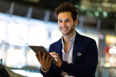 Genç yönetici, modern bir şehirde geceleri dijital tablet kullanıyor.
