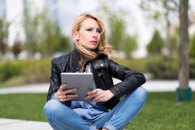 Bir bankta oturan tablet ile kız