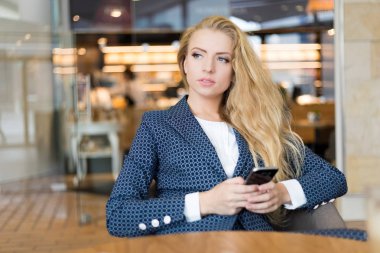Genç iş kadını akıllı telefonunu web içeriğini taramak ve mesajlar göndermek için kullanıyor