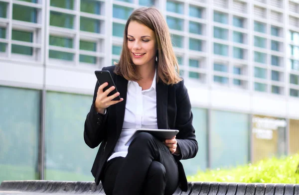 Dijital Tablet Kullanan Gülümseyen Kadını Bankta Oturuyor Akıllı Telefonunu Kullanıyor — Stok fotoğraf