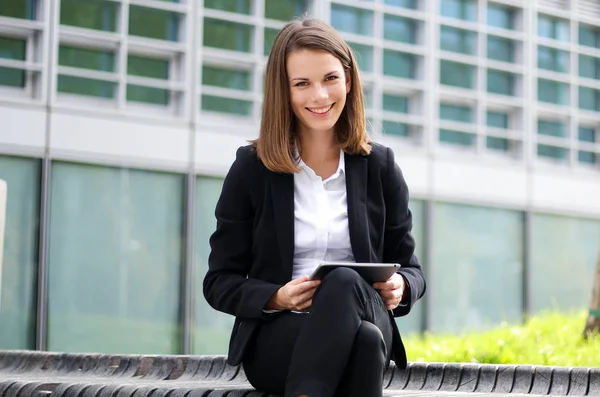 ベンチに座ってデジタルタブレット屋外を使用して笑顔ビジネス女性 — ストック写真