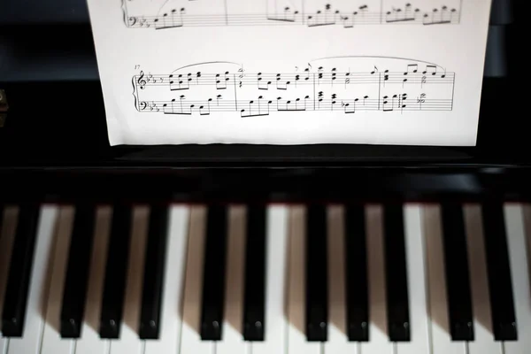 Closeup of a piano keyboard and a music sheet