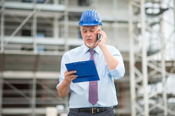Architekt Rozmawiający Przez Telefon Komórkowy Przed Placem Budowy Podczas Czytania — Zdjęcie stockowe