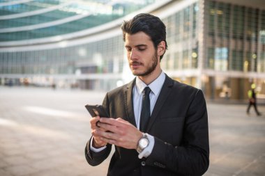 İş adamının elinde cep telefonu var. Uygulama SMS iletisi kullanıyor.