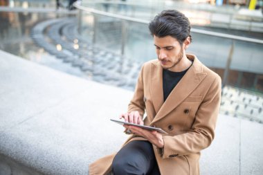 Genç adam tabletini şehir dışında kullanıyor.