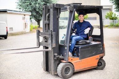Endüstriyel bir fabrikada forklift kullanan yakışıklı bir inşaat işçisi.