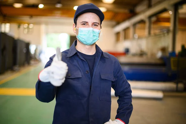 マスクをつけて親指を立てる工業プラントの労働者の肖像画 コロナウイルスの概念 — ストック写真