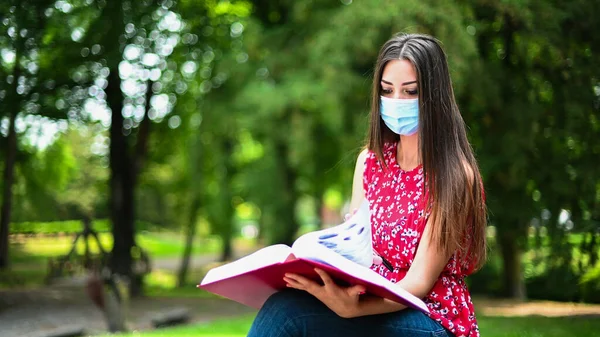 Hermosa Estudiante Universitaria Leyendo Libro Banco Parque Usando Una Máscara —  Fotos de Stock