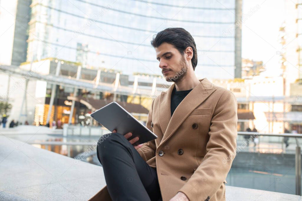 Young man using his tablet outdoor in a city