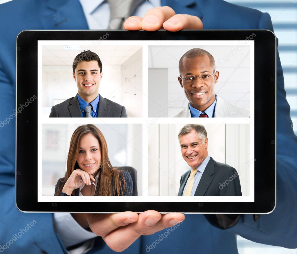Businessman holding a tablet during a remote call, smiling faces of business people on the screen